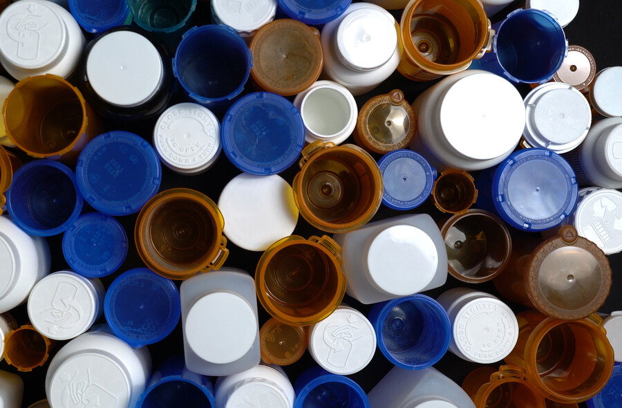 Many empty prescription pill bottles, some with caps removed.