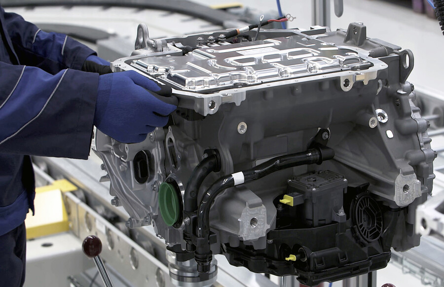 Gloved hands in a car factory working on an electric vehicle motor.