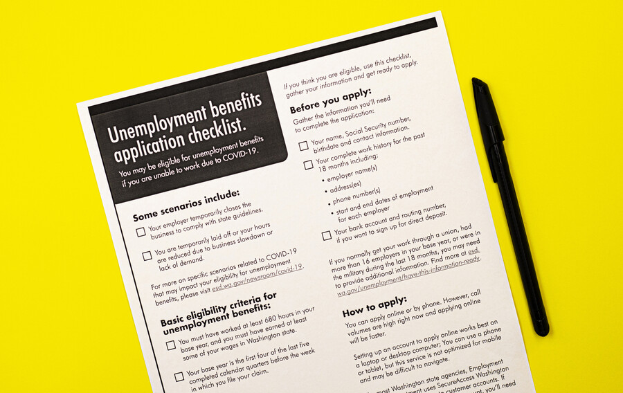An “Unemployment benefits application checklist” form on a surface next to a pen.