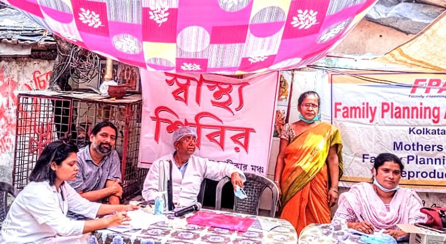 TJ Ghose sits with three other people at a table. Banners behind them read, family planning 