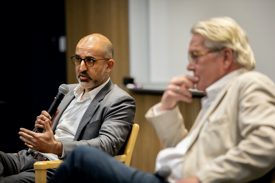Middle East Center Director John Ghazvinian speaks into a microphone, sitting next to Tor Wennesland