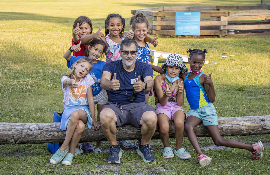 Al Filreis sitting on a log with seven young campers.