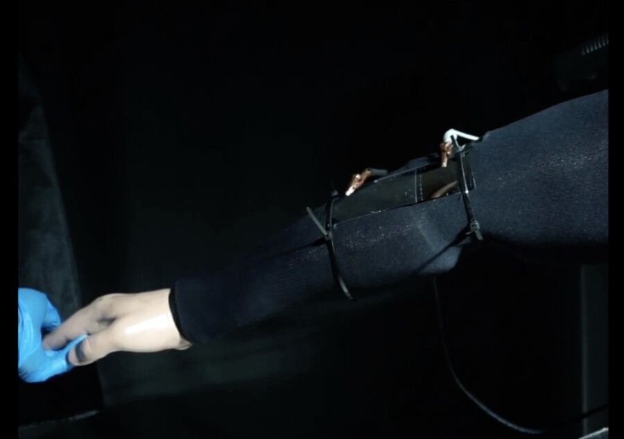 A robotic arm holding the hand of a mannequin.