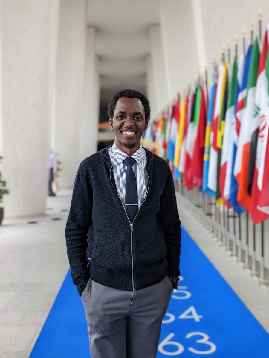 David Kato stands in front of a row of flags of different nations.