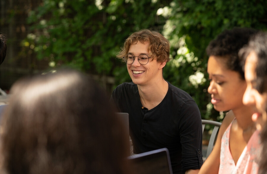 Tom Etienne with students sitting outside.