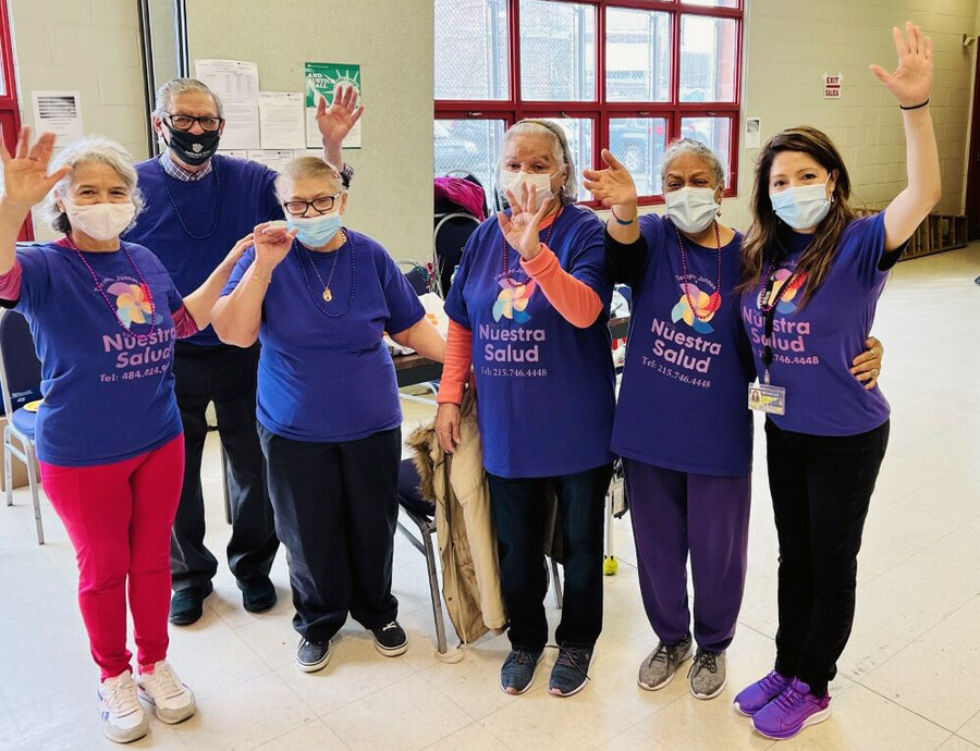Four older Latinx people with Ruby Rivera and Adriana Perez at a community health center. 