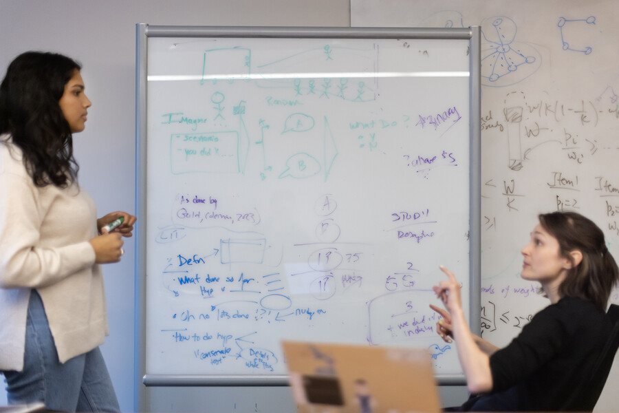 gandhi and kiyawat in front of a white board with calculations