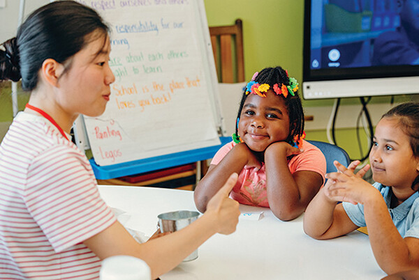 A Penn student teaches two elementary school students in a classroom.