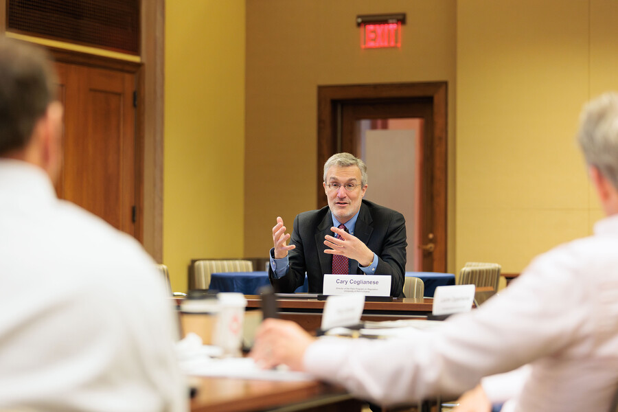 Cary Coglianese speaking to two people at a conference table.