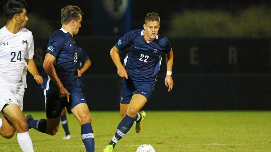 Stas Korzeniowski, wearing his blue Penn jersey, kicks the ball up the field during a game.