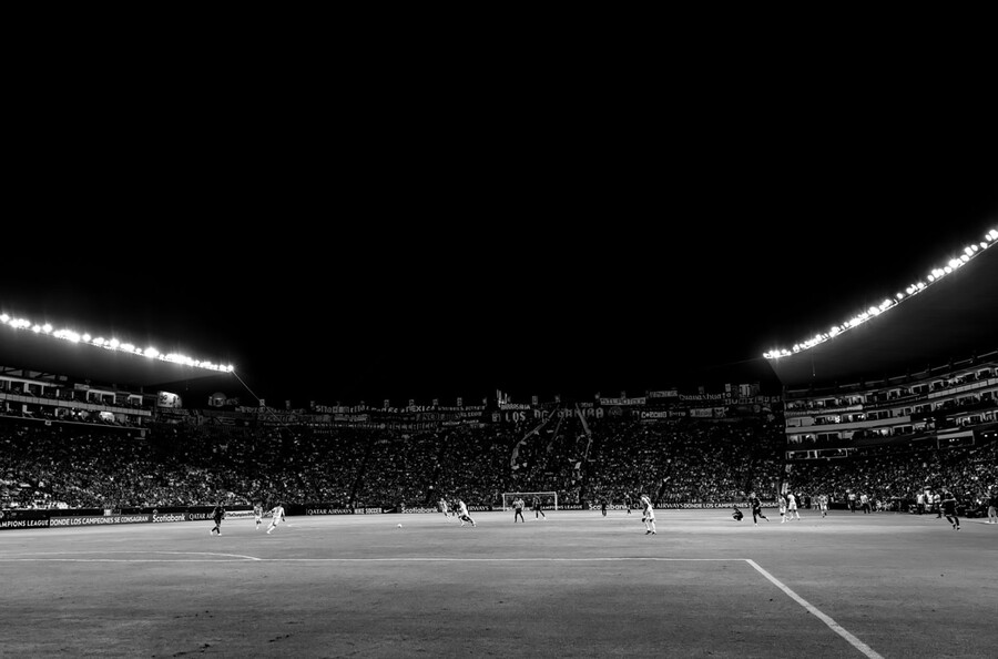 Soccer players on a soccer pitch at night.