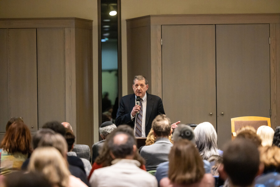 Steven Weitzman standing and speaking into a microphone