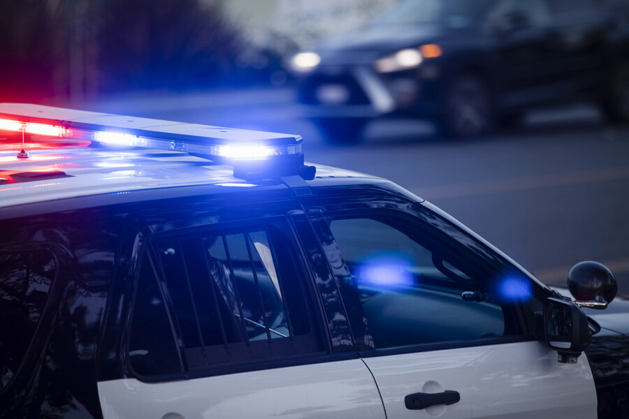 A police car with its lights on the roof.