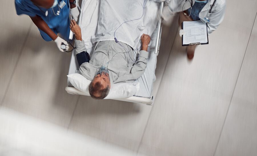 A patient being wheeled in the hospital flanked by two medical professionals.