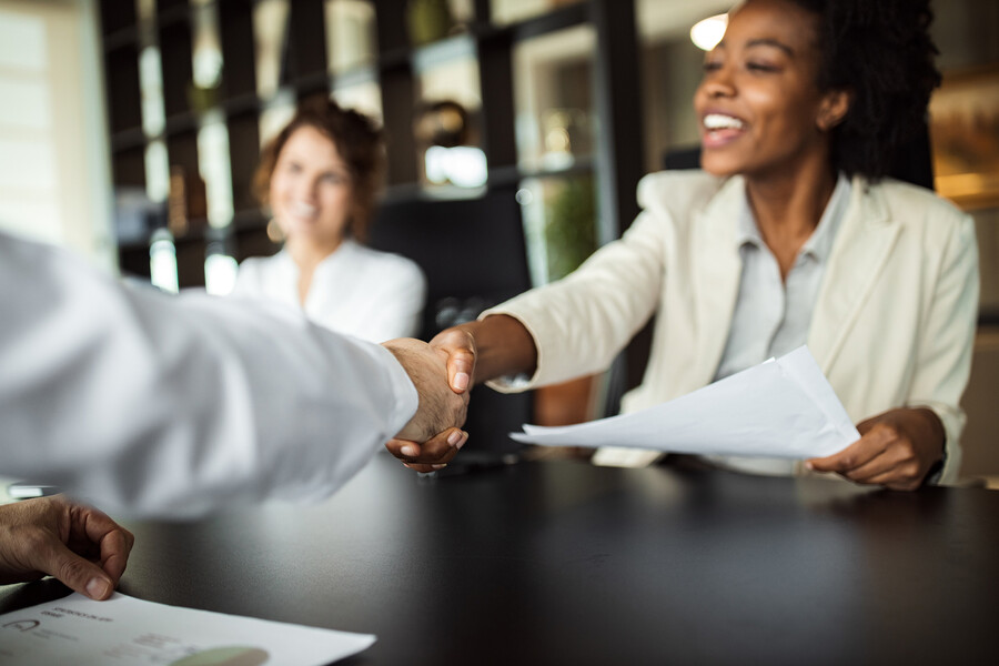 A person shaking hands with an interviewer at a job interview.