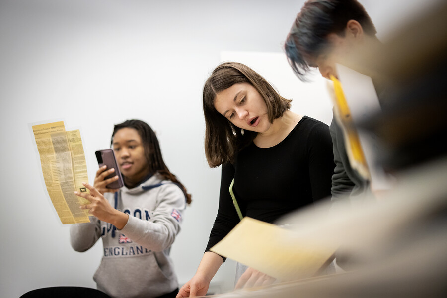 Three students looking at gender, sexuality, and women’s studies archival material.