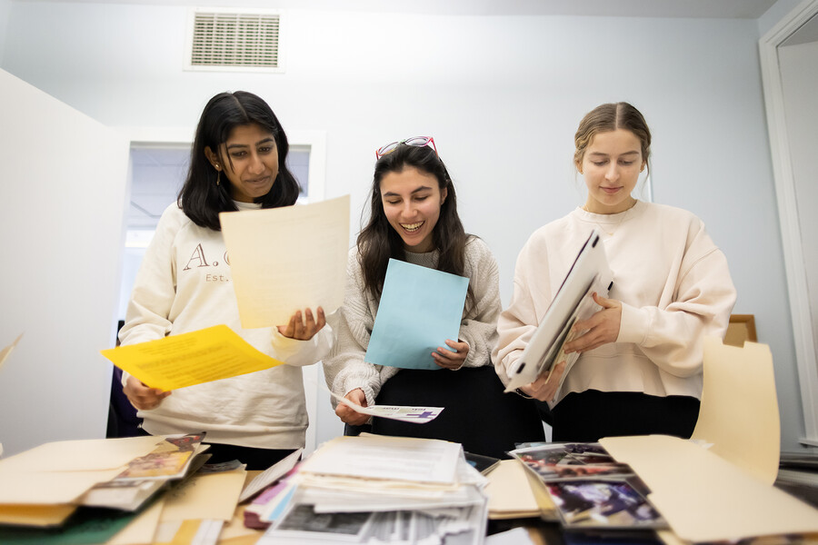 Three students looking at gender, sexuality, and women’s studies archival material.