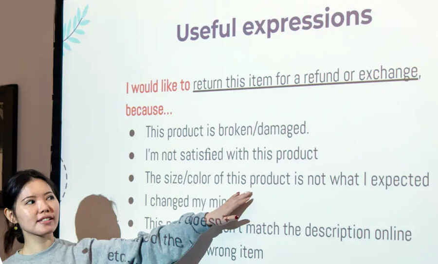 A person at a projector screen teaching English.