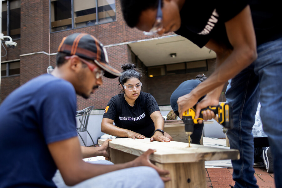 Studio+ workers drilling wood in the courtyard.