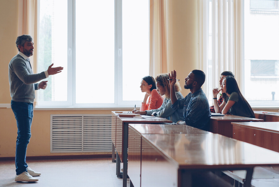 A teacher in a classroom lecturing community college students.