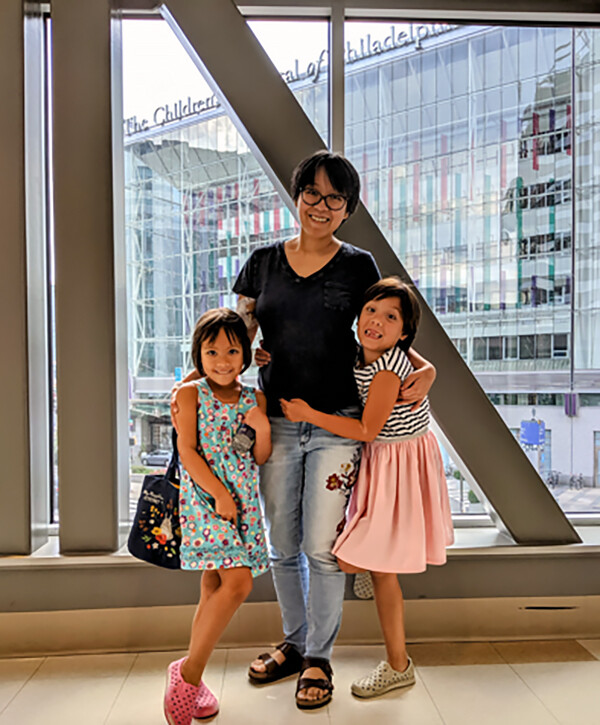 Becky Yu in a Penn Medicine building with her two daughters.