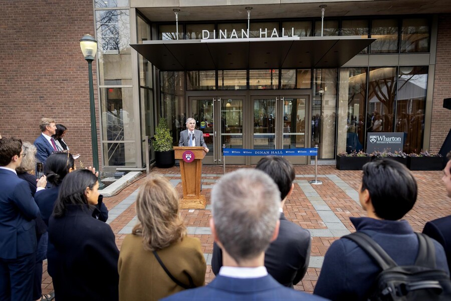 Trustee Jamie Dinan stands behind a lectern as he speaks to a crowd in front of Dinan Hall.