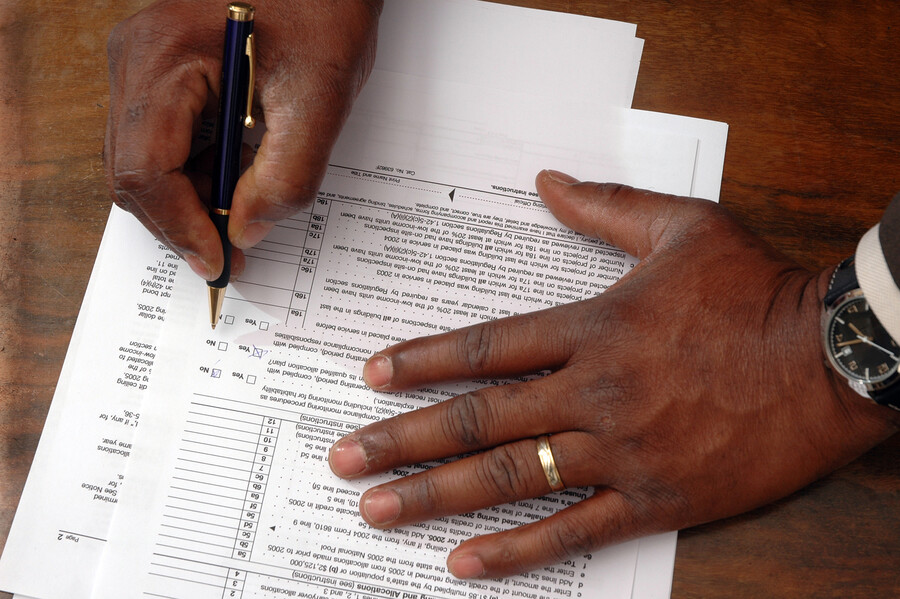 A person’s hands filling out a tax form in pen.