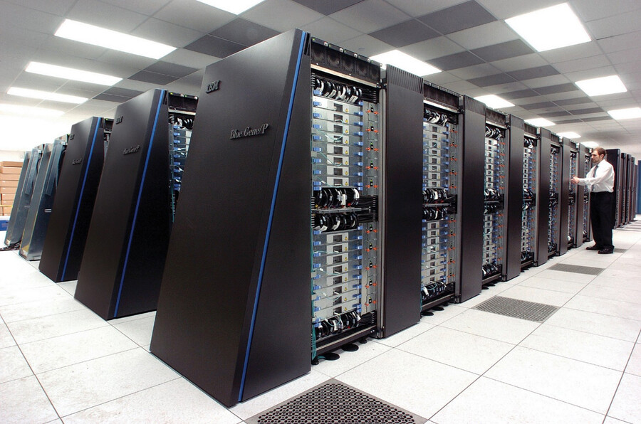 A person standing in a room with a giant supercomputer.