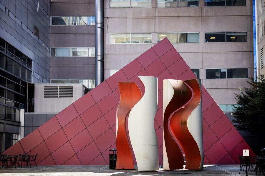 A red pyramid stands in a courtyard at the Hospital of the University of Pennsylvania behind the Quadrature sculpture.