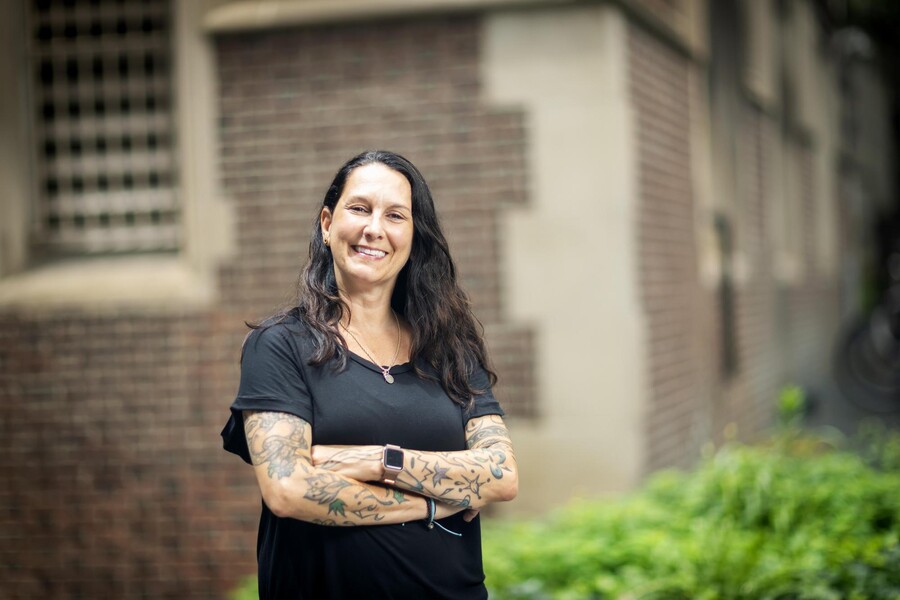 Amy Onorato standing with arms crossed outdoors, while smiling and facing forward.