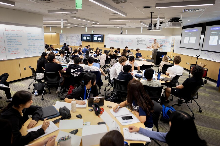 High School students in the Economics Academy sit in a classroom listening to a professor.