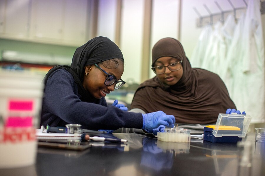 Two high school students woking with pipettes in a science classroom.