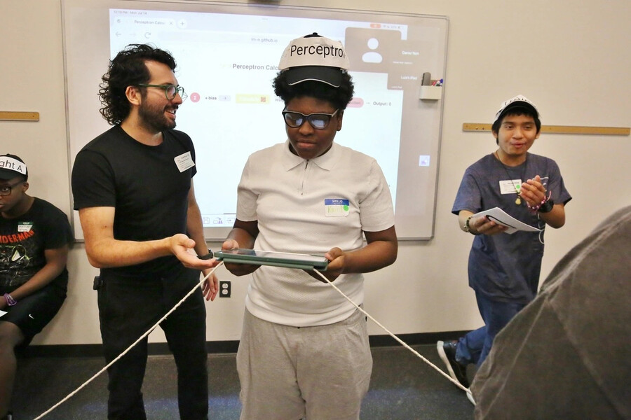 Morales-Navarro assists a student who holds a computer tablet