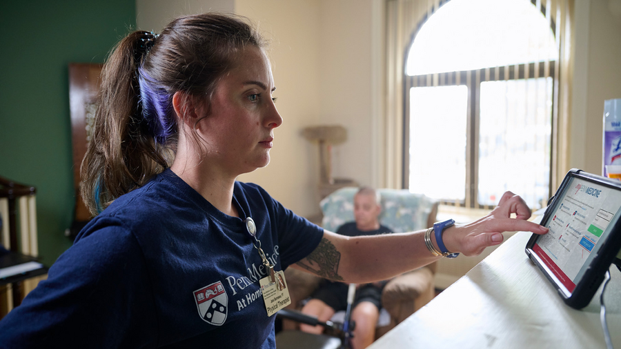 Physical therapist Jana Barmasse reviews information on a tablet at Mike Desalis’ home.