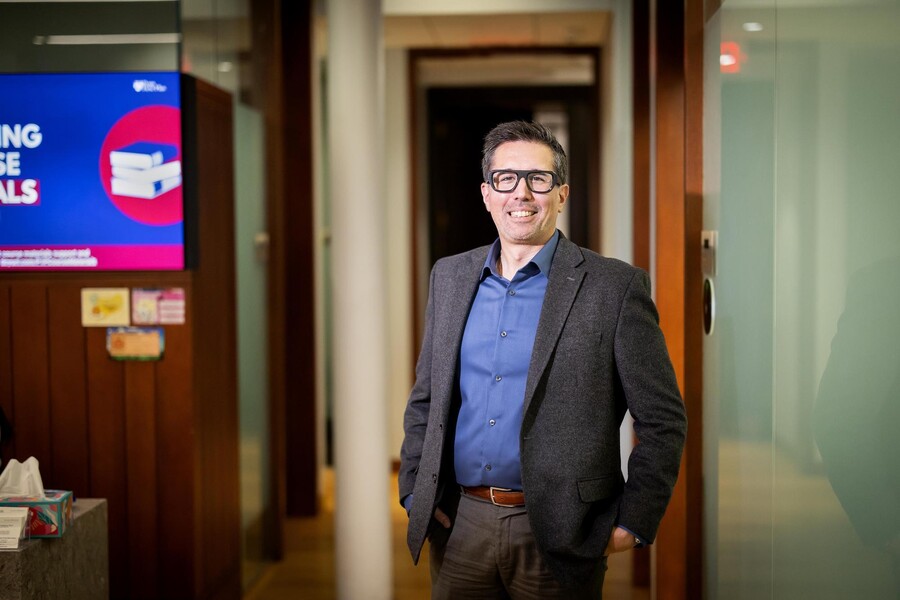 Marc Lo, the inaugural executive director of Penn First Plus (P1P), standing and smiling in the P1P office