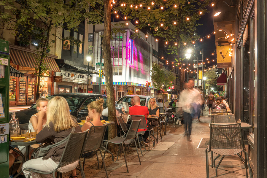 People dining on a well-lit Philly sidewalk at night.