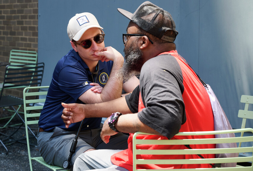Zachary Kosak talks with Danny at a table outdoors.