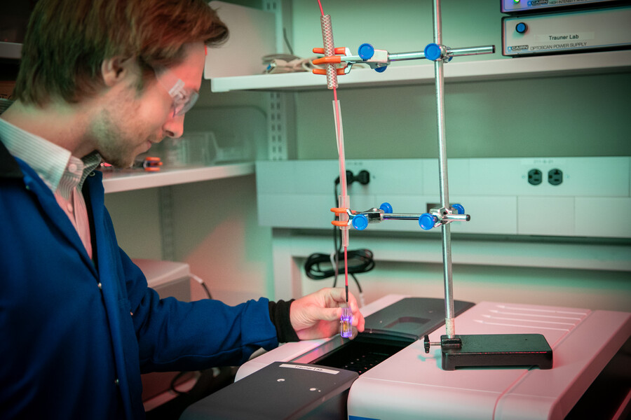 Researcher Michael Zott holds a glass tube over a light source.