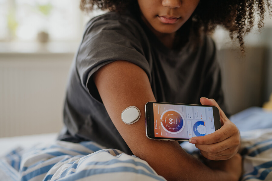A teen takes a blood sugar reading with an app on their phone.