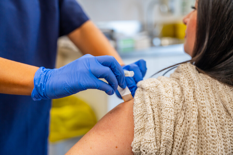 A person getting a bandage on their arm after a flu shot from a medical provider.