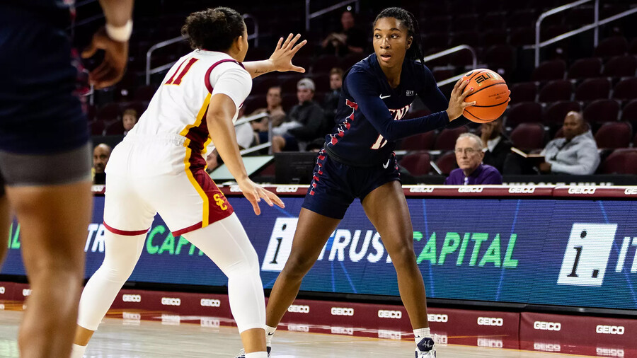 Simone Sawyer holds the ball along the sideline while guarded by a defender.