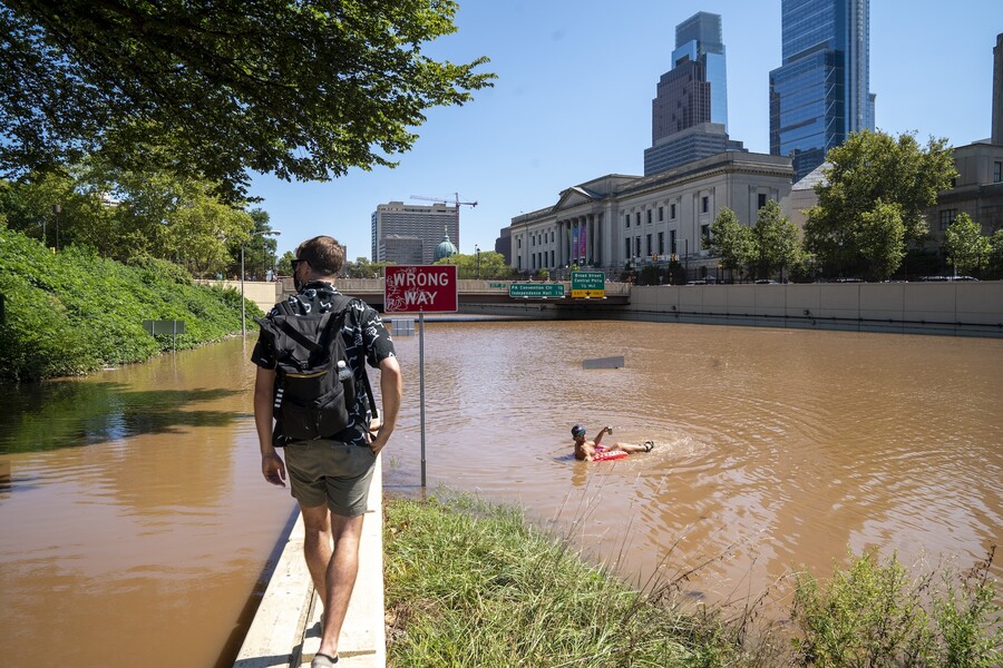 Person walks along lane divider towards another person in an inflatable.