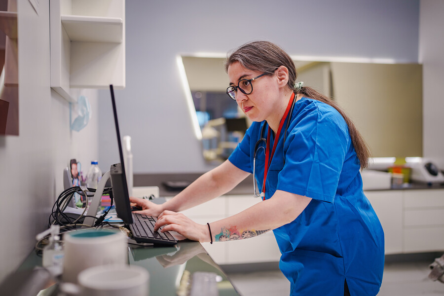 A nurse typing on a desktop computer.
