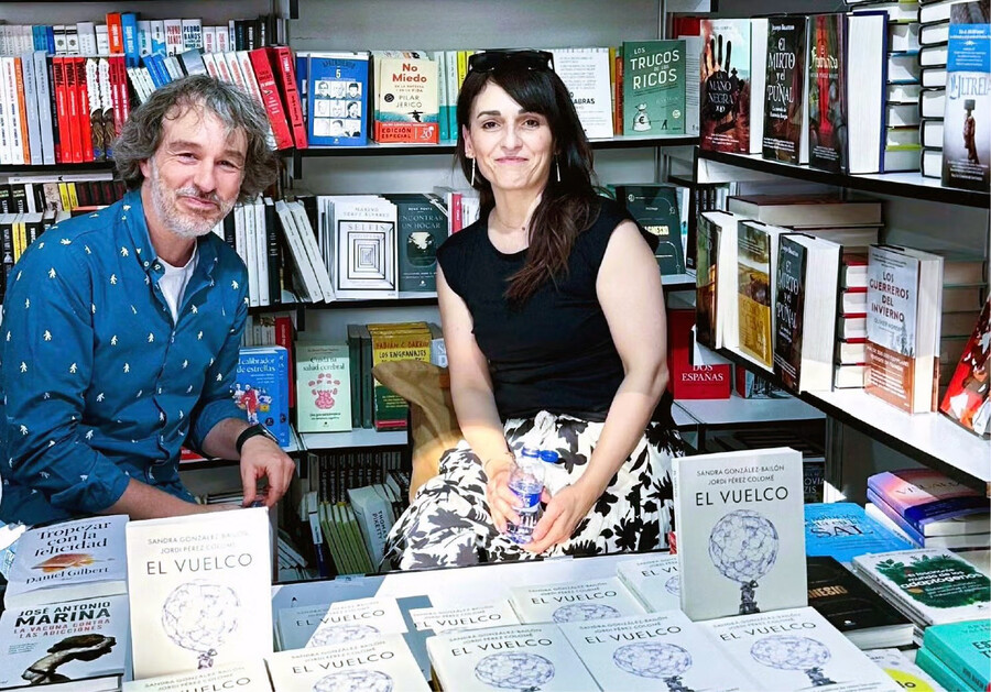 Jordi Pérez Colomé and Sandra González-Bailón seated at a bookstore with copies of their book.