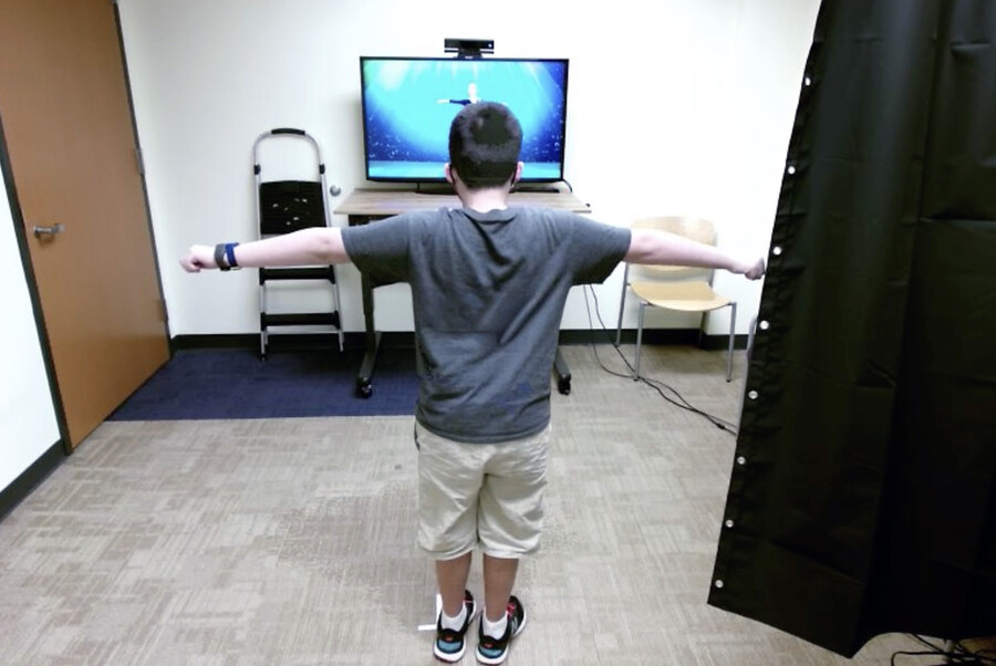 A child follows movements from a video in a clinical office setting.