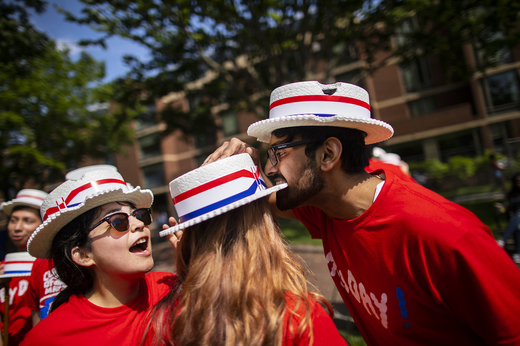 students bite hats as part of a hey day tradition