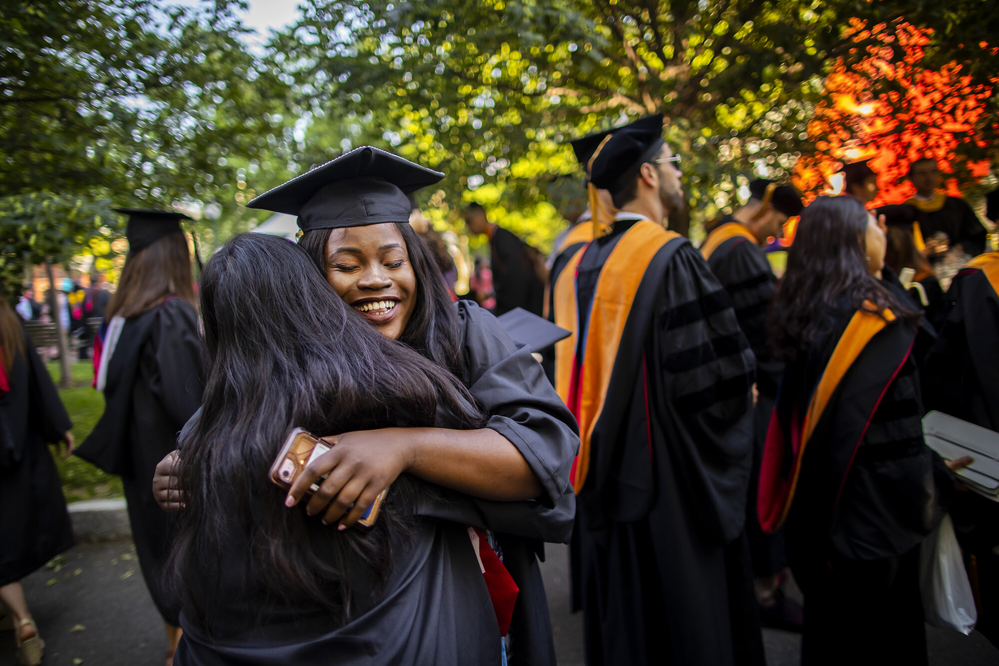 Two graduates embrace in a hug on Locust Walk.