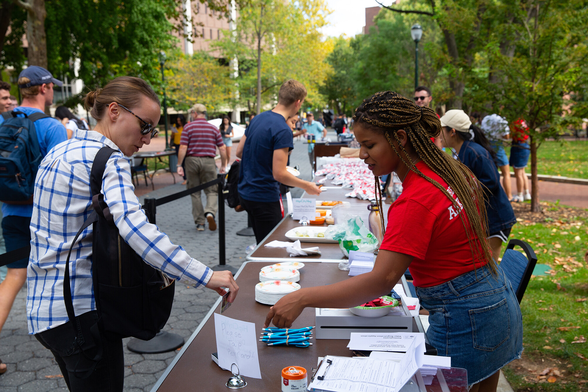 A volunteer with Penn Leads the Vote talks with a student outside on College Green