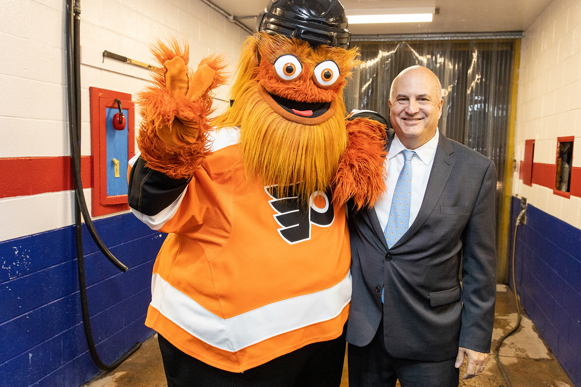 Gritty flashes the peace sign alongside Craig Carnaroli at the Penn Skating Rink