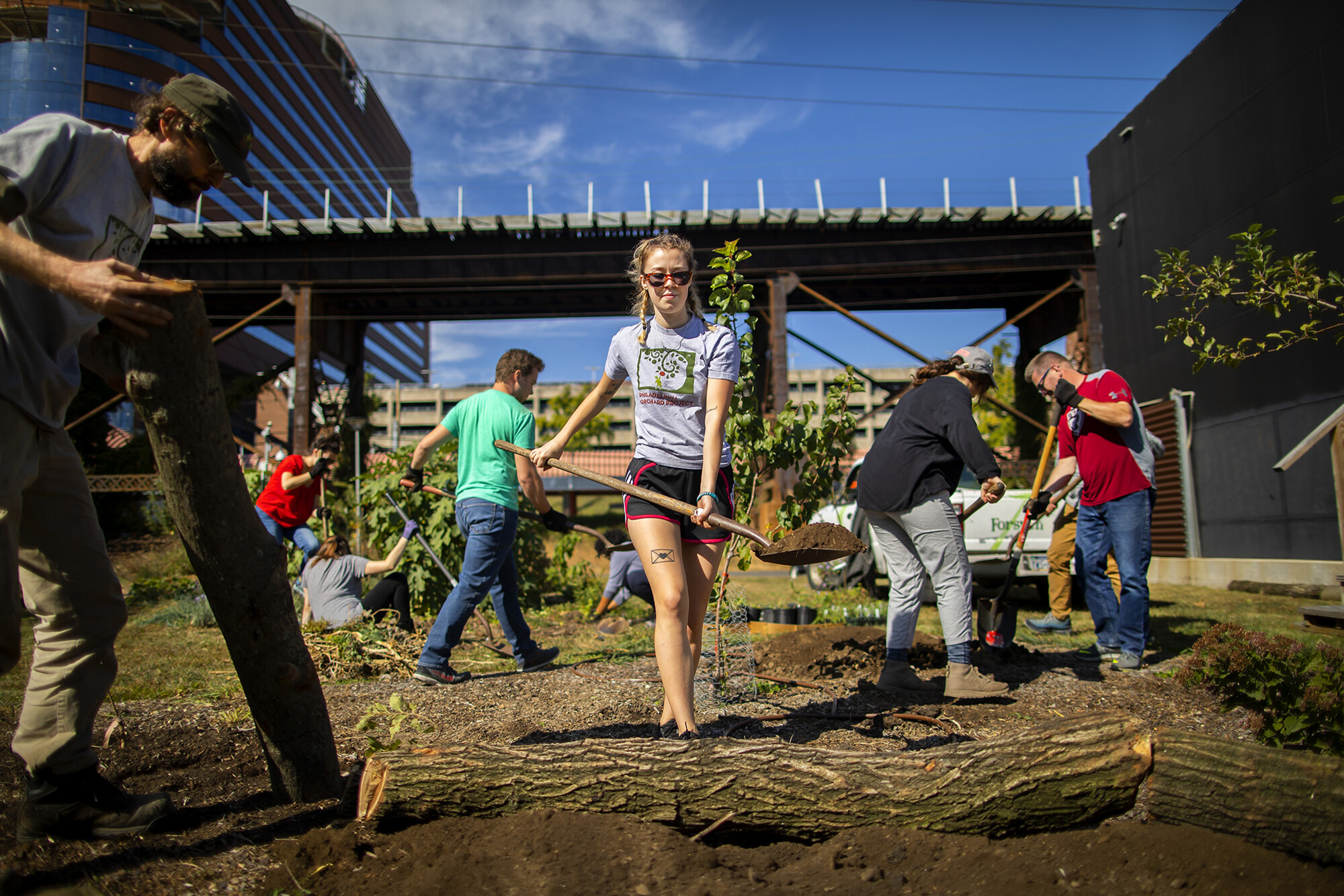 shoveling dirt at the penn park orchard with patient pavilion in the background